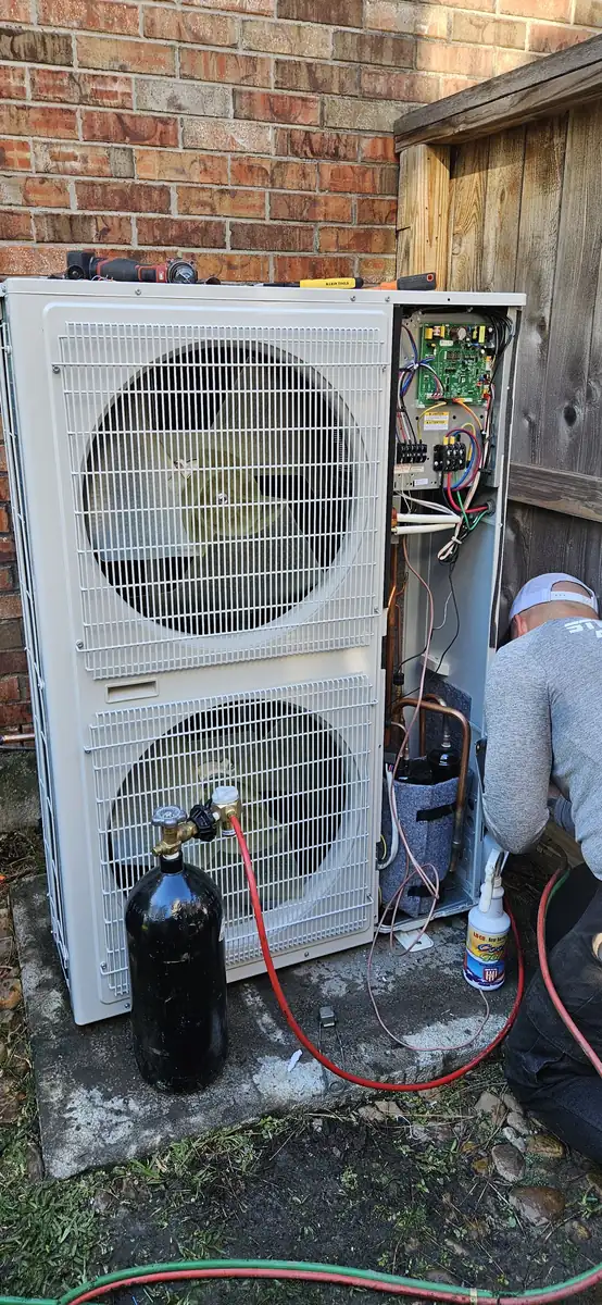 A Steadfast technician working on a residential condenser with the electrical panel open
